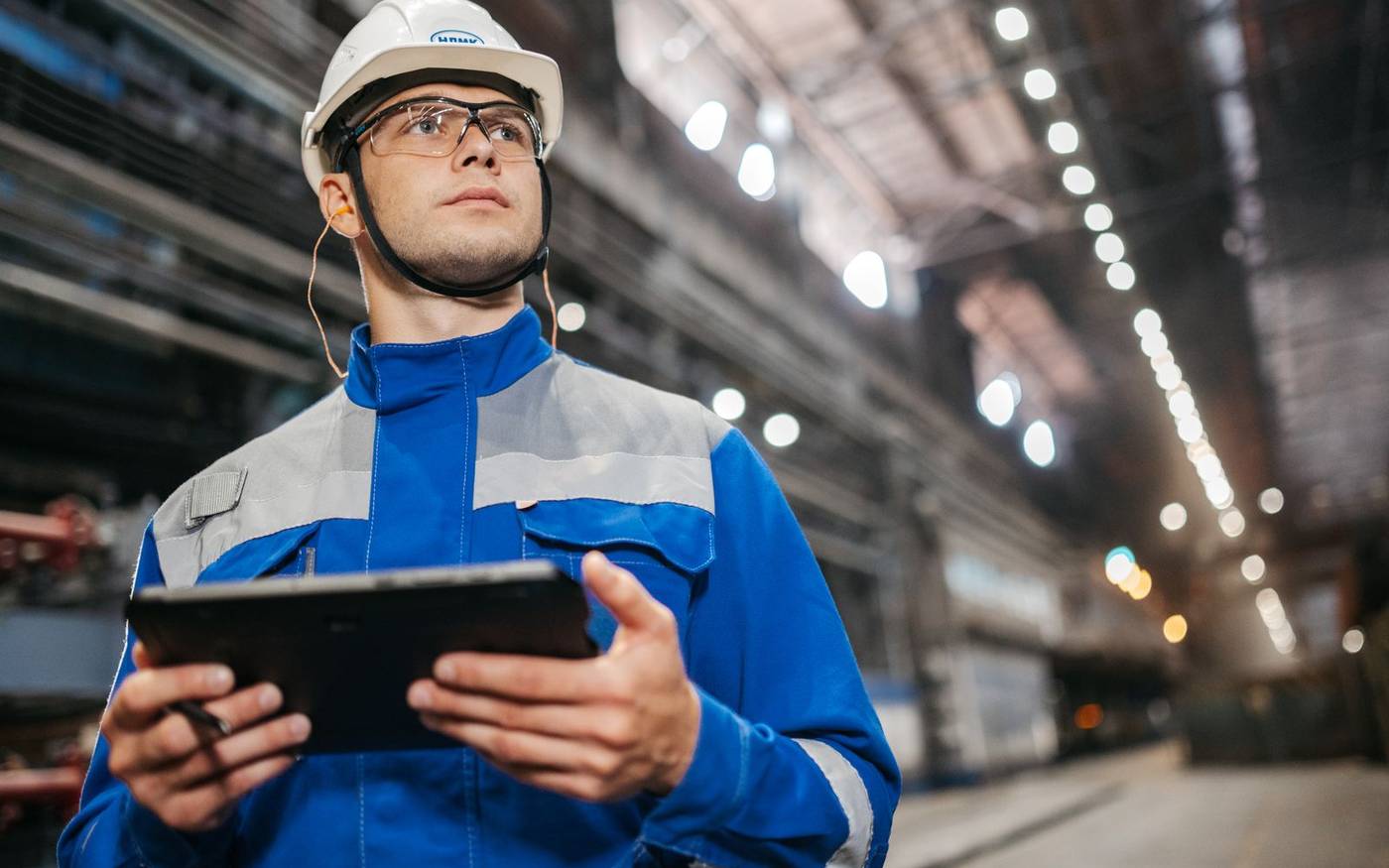 Technik v priemyselnej hale kontroluje údaje na tablete